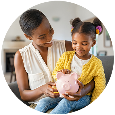 A smiling woman and young girl hold a pink piggy bank together. 